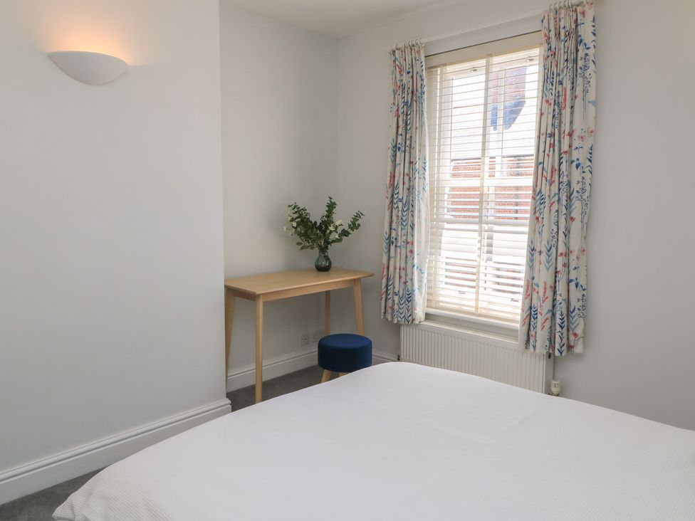 A bedroom with a bed and a table at Cobblers Cottage in Lymington