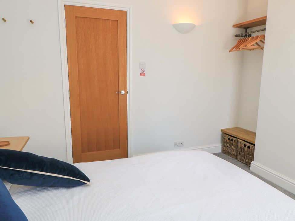 A bedroom featuring a bed and wooden door at Cobblers Cottage in Lymington