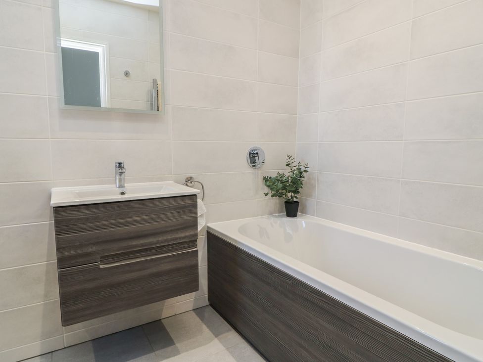 A bathroom with a bathtub and vanity unit at Cobblers Cottage in Lymington