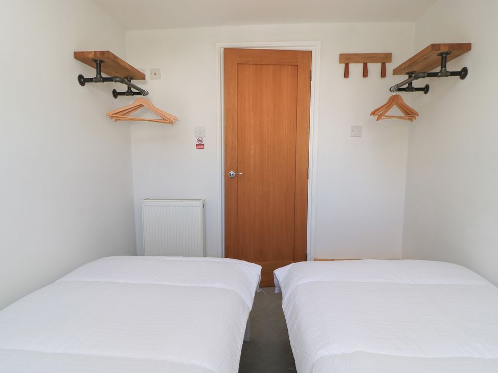 A bedroom with two beds and a door at Cobblers Cottage in Lymington