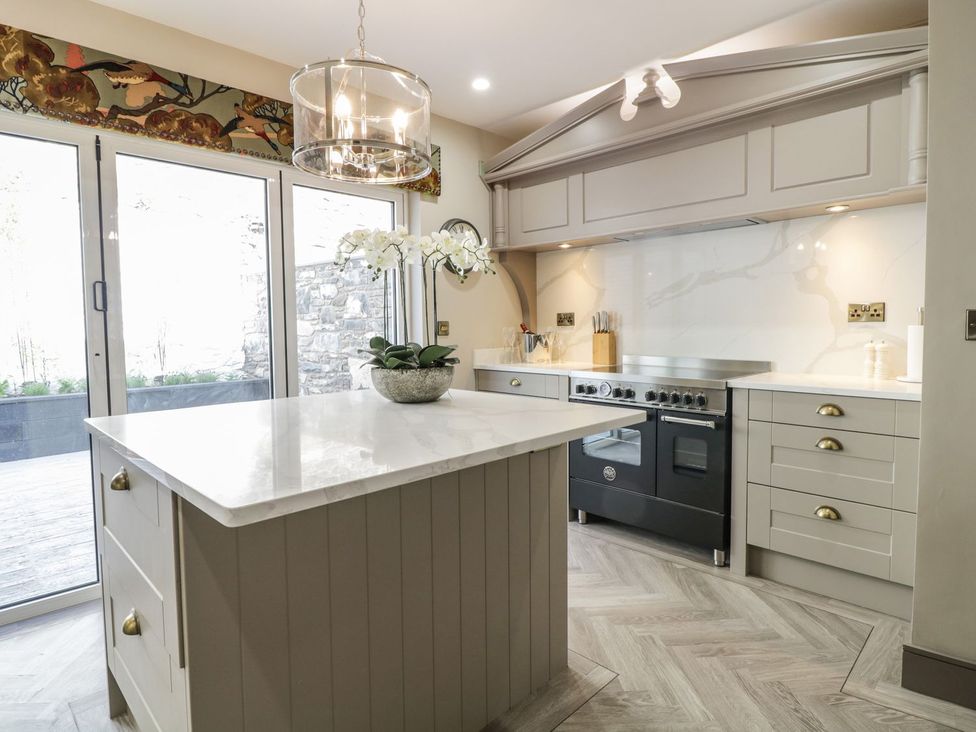 A kitchen with a stove, island, and orchid plant at 2 Llewelyn Street, Conwy