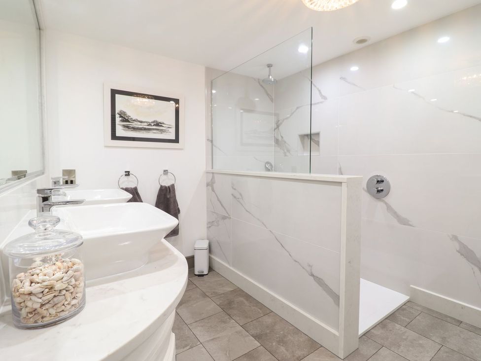 A bathroom with sinks, shower area, and wall art at 2 Llewelyn Street Conwy