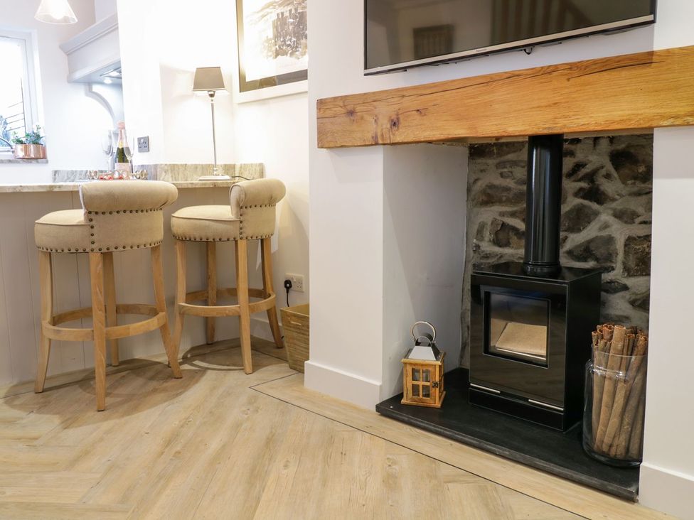 A kitchen with bar stools and a wood stove at 8 Crown Lane in Conwy