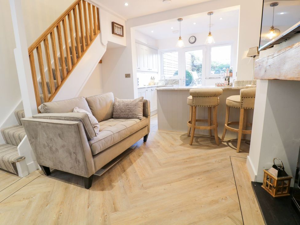 A living room with a sofa and bar stools at 8 Crown Lane in Conwy