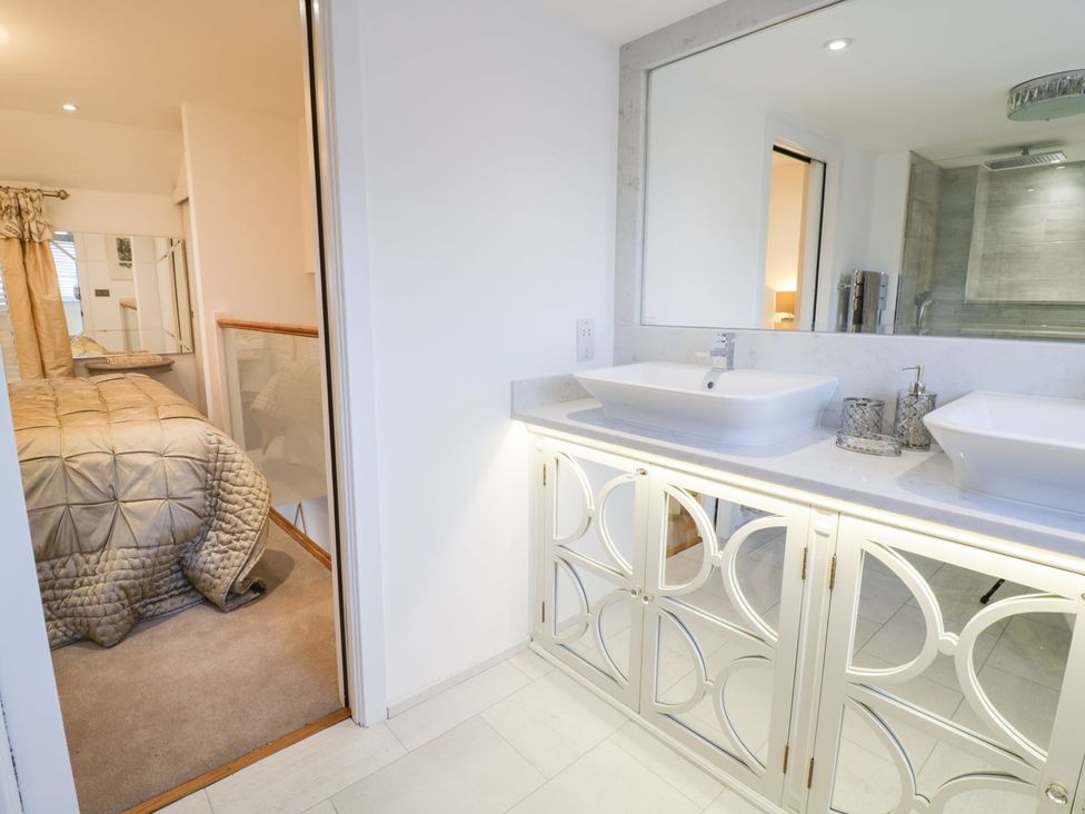 A bathroom with two sinks and a door to the bedroom at 8 Crown Lane, Conwy