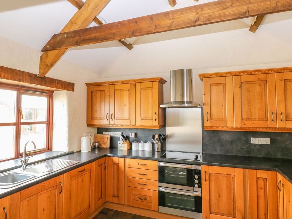 A kitchen with wooden cabinets and stainless steel appliances at Maerdy Cwtch Haverfordwest