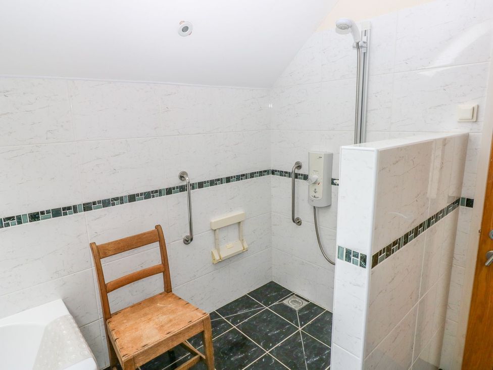 A bathroom with shower and chair at Maerdy Cwtch in Haverfordwest