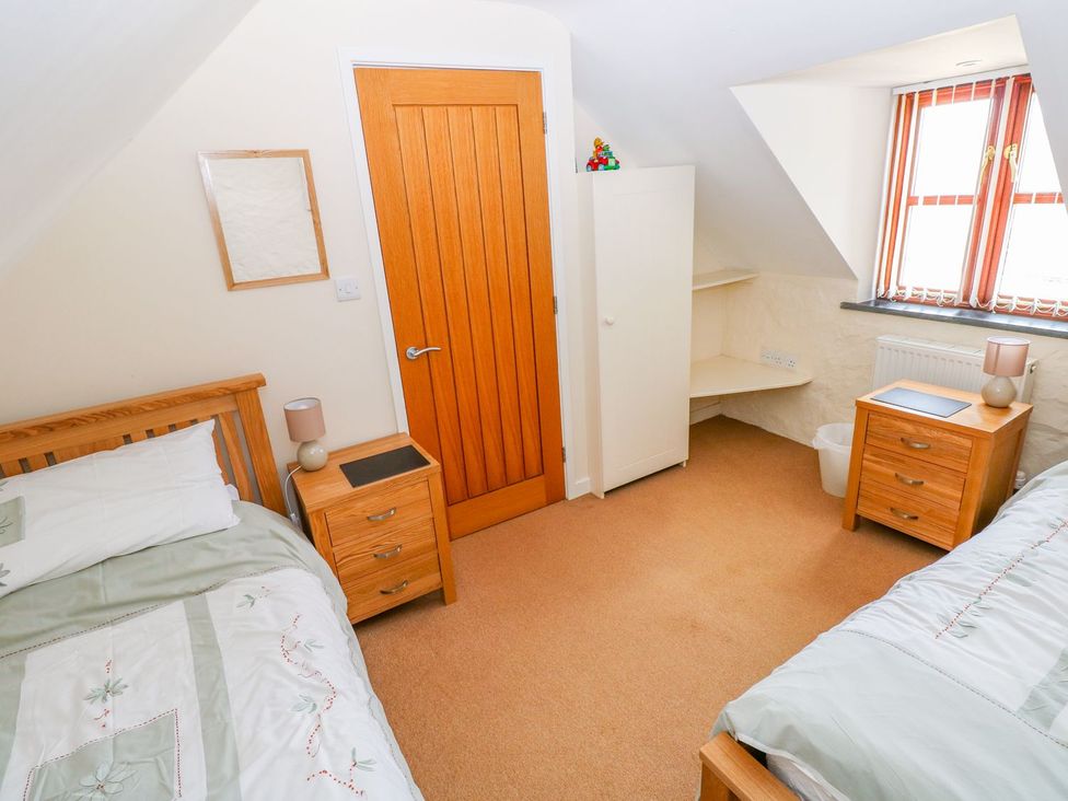 A bedroom with two beds and a wardrobe at Maerdy Cwtch in Haverfordwest