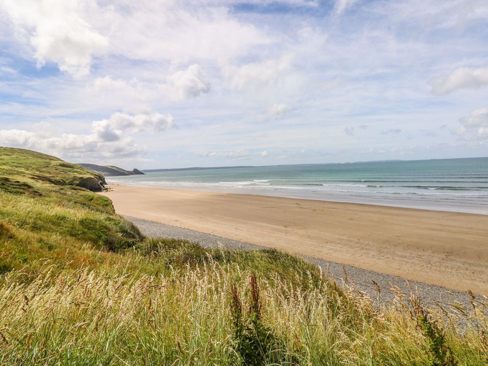 A beach scene with grass and waves at Maerdy Cwtch in Haverfordwest