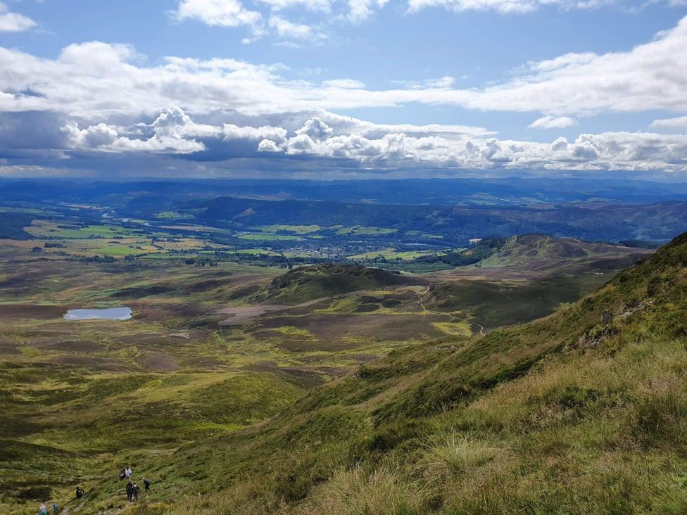 A scenic view of mountains and valleys with a lake and walking paths in Pitlochry