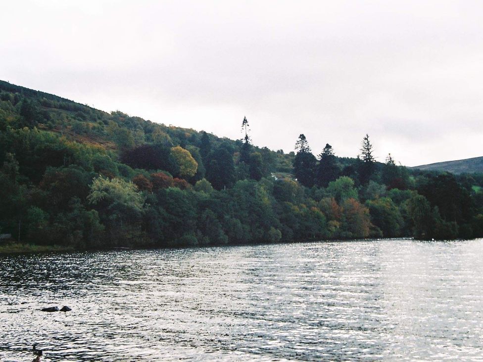 A lake with trees and hills around at Stylish Highland retreat in the heart of town Pitlochry