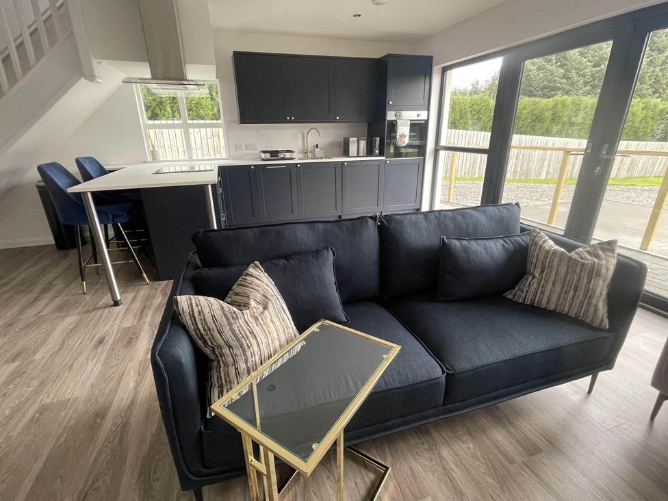 A living room with a sofa and kitchen area at Stylish NC500 base with panoramic views Inverness
