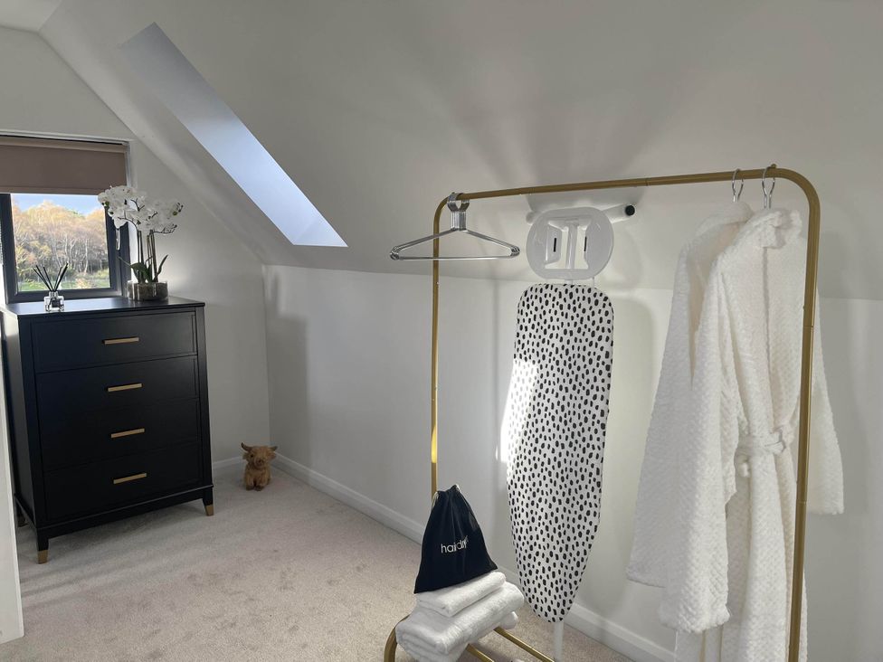 A bedroom with a dresser and an ironing board at Stylish NC500 base with panoramic views in Inverness