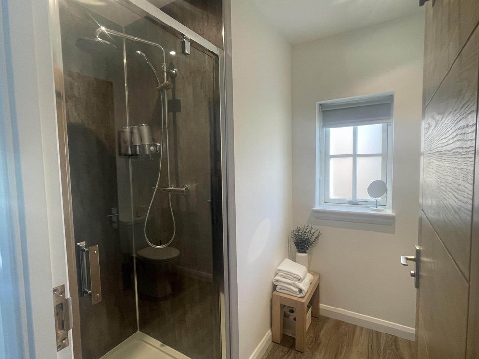 A bathroom with a shower, toilet, and a small window at Stylish NC500 base with panoramic views Inverness
