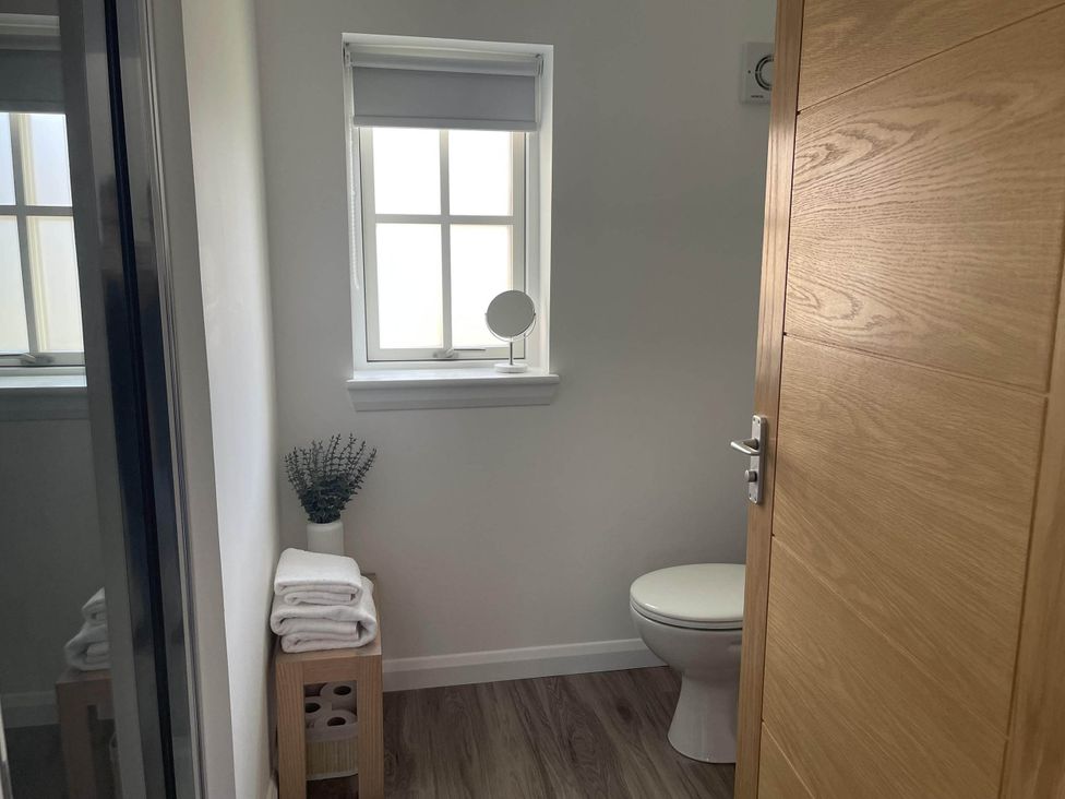 A bathroom with a toilet, mirror, and towels at Stylish NC500 base with panoramic views Inverness