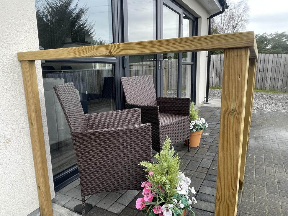 Two chairs and flower planters in a seating area at Stylish NC500 base with panoramic views in Inverness