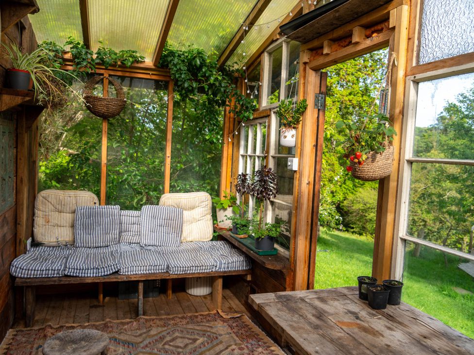 A conservatory with a sofa and plants at Hapus Yurt - Two Beautiful Yurts and Barn Cottage
