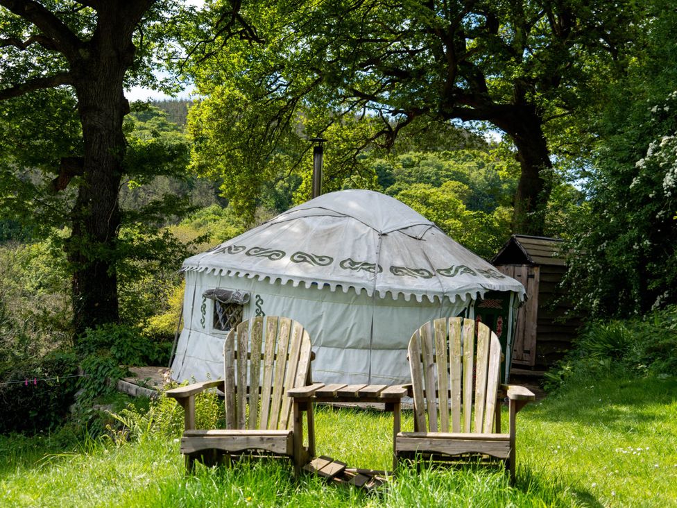 An outdoor area with a yurt and wooden chairs at Hapus Yurt - Two Beautiful Yurts and Barn Cottage