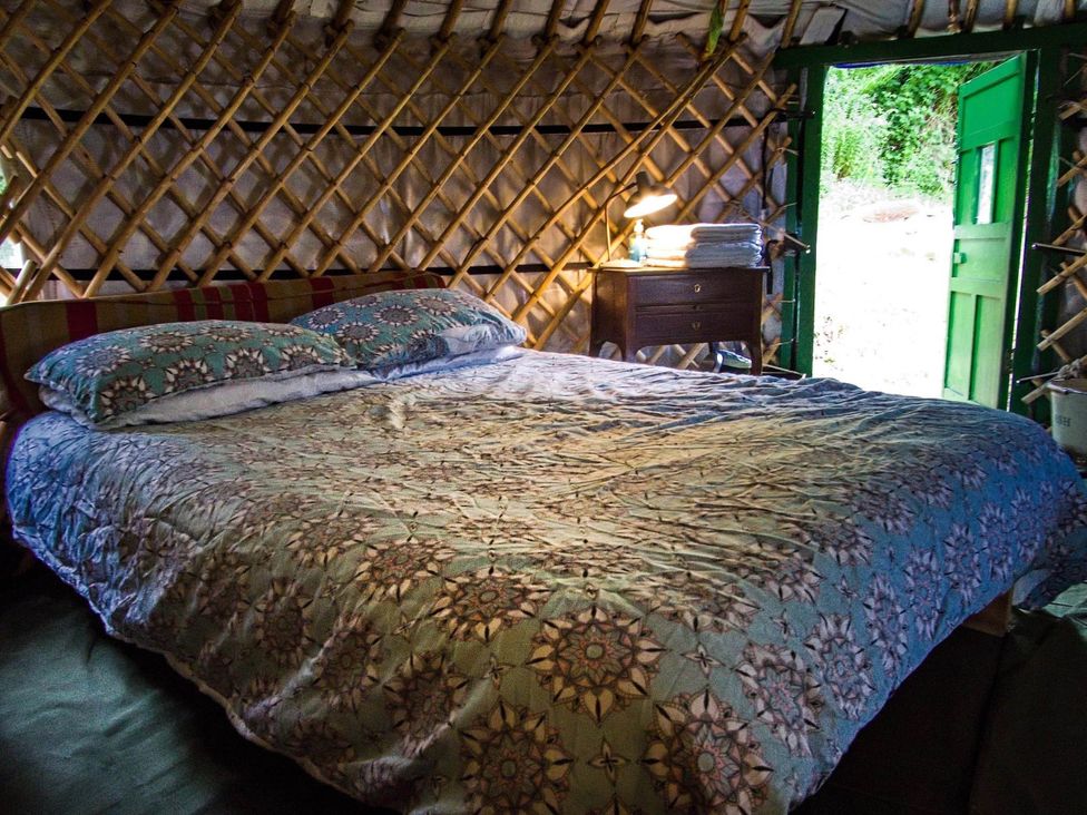 A bedroom with a bed and nightstand at Hapus Yurt - Two Beautiful Yurts and Barn Cottage