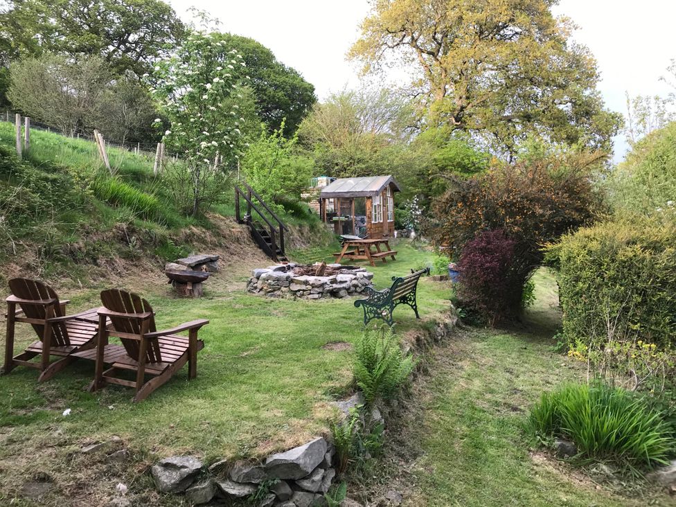 An outdoor garden with chairs, a fire pit, and a table at Hapus Yurt - Two Beautiful Yurts and Barn Cottage