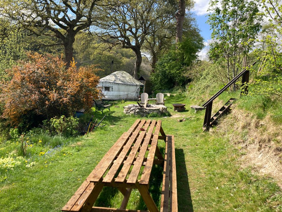 A garden with a wooden picnic table and yurt at Hapus Yurt - Two Beautiful Yurts and Barn Cottage