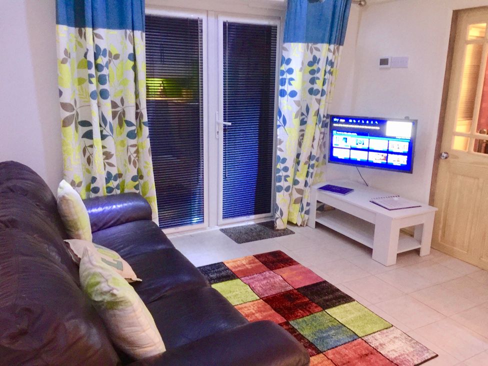 A living room with a sofa, television, and curtains at Zip Cottage Sleeps 2-3 climb snowdon zip world