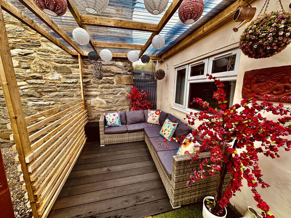 An outdoor seating area with a sofa and decorative plants at Zip Cottage Sleeps 2-3 climb snowdon zip world
