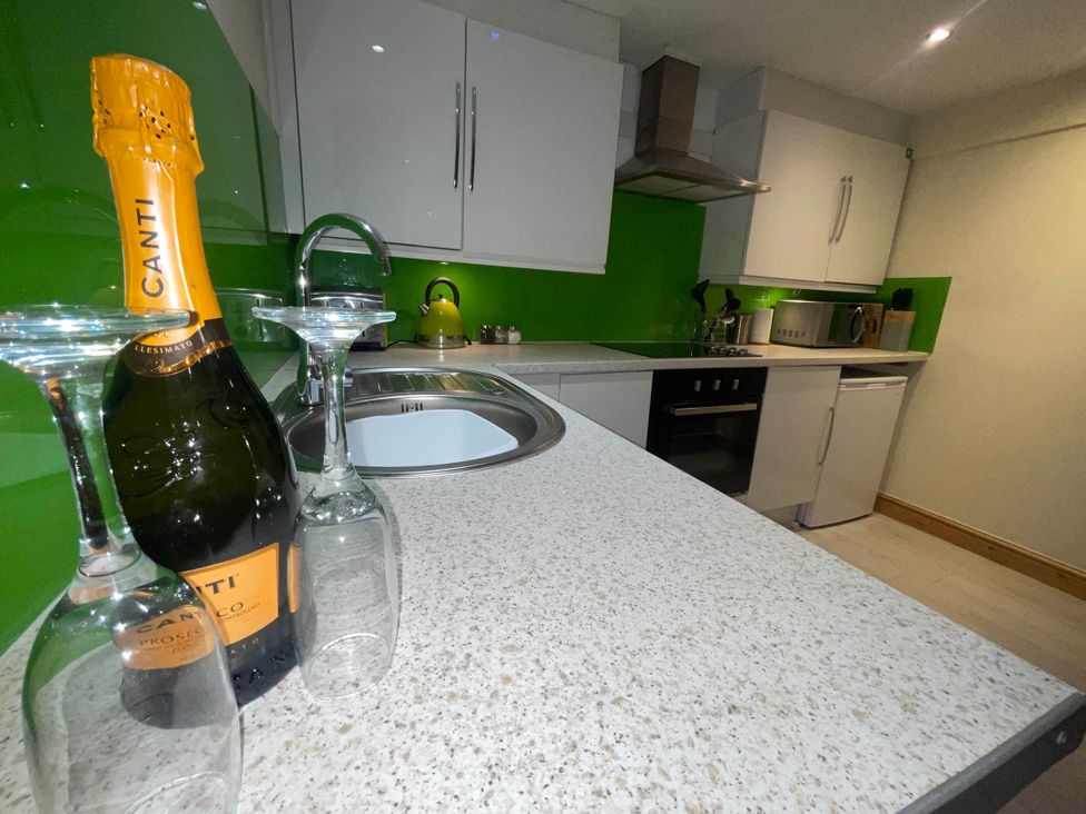 A kitchen with a sink, champagne bottle, and glasses at Zip Cottage Sleeps 2-3 climb snowdon zip world