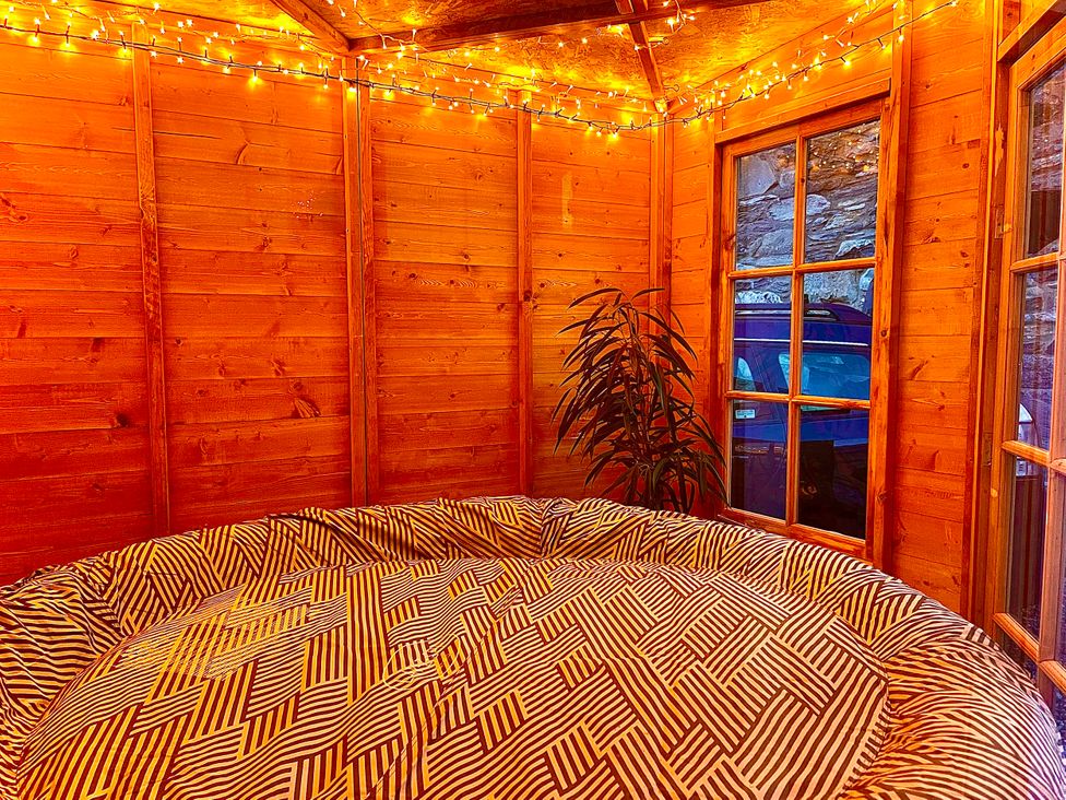 A garden room with a round bed and wooden walls at Zip Cottage Sleeps 2-3 climb snowdon zip world