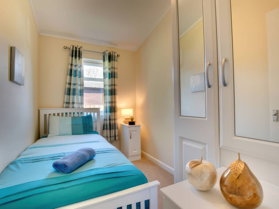 A bedroom with a single bed and wardrobe at Pet-friendly lodge with hot tub near the coast