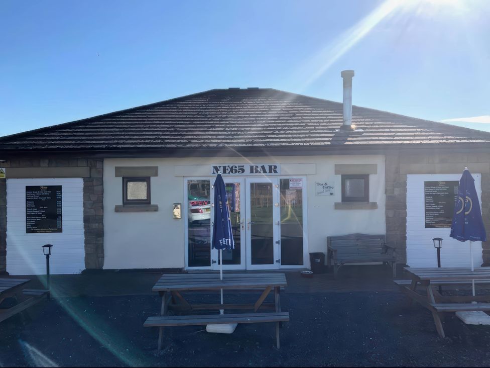 An exterior view of a bar with tables and umbrellas at a bar location