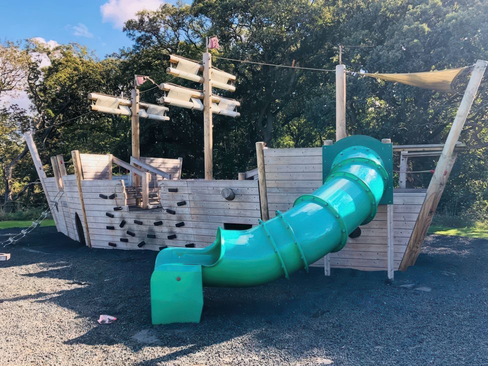 A playground structure shaped like a ship with a slide at a park