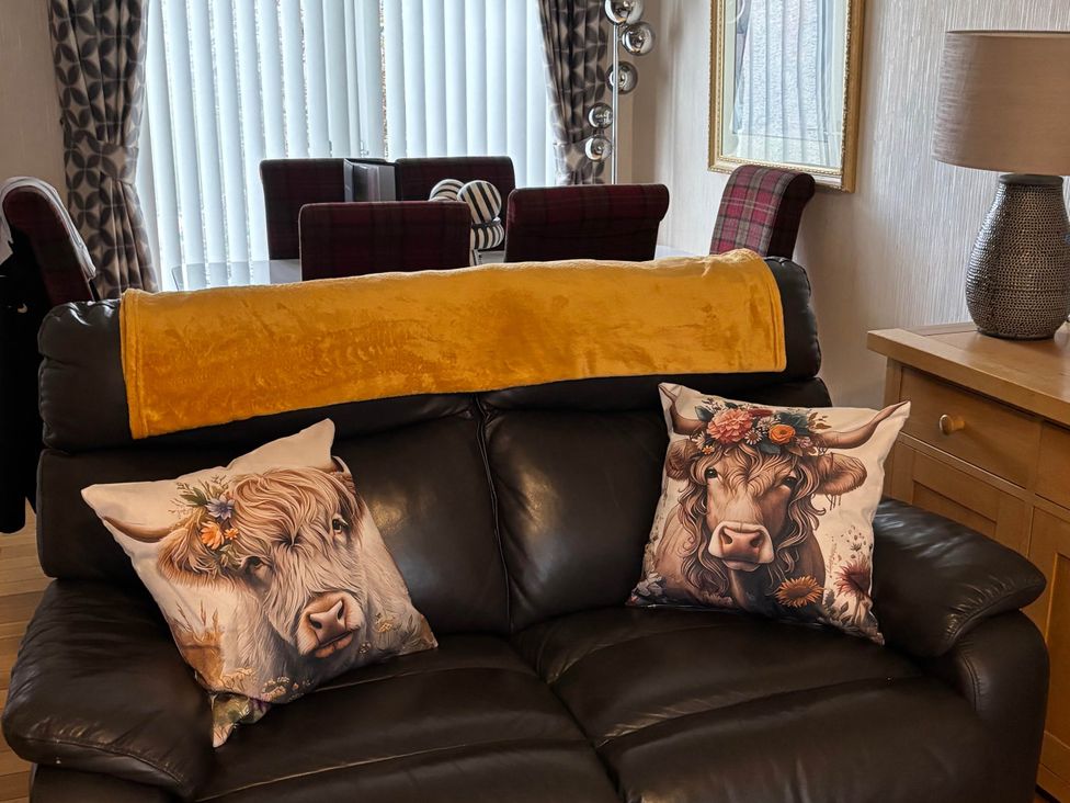 A living room with a sofa and decorative cushions at Spacious family base with garden near Loch Ness
