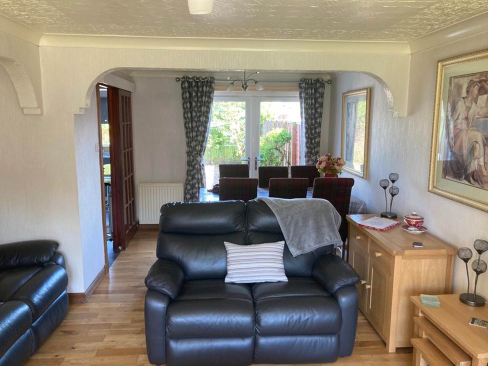 A living room with a sofa, table and chairs at Spacious family base with garden near Loch Ness