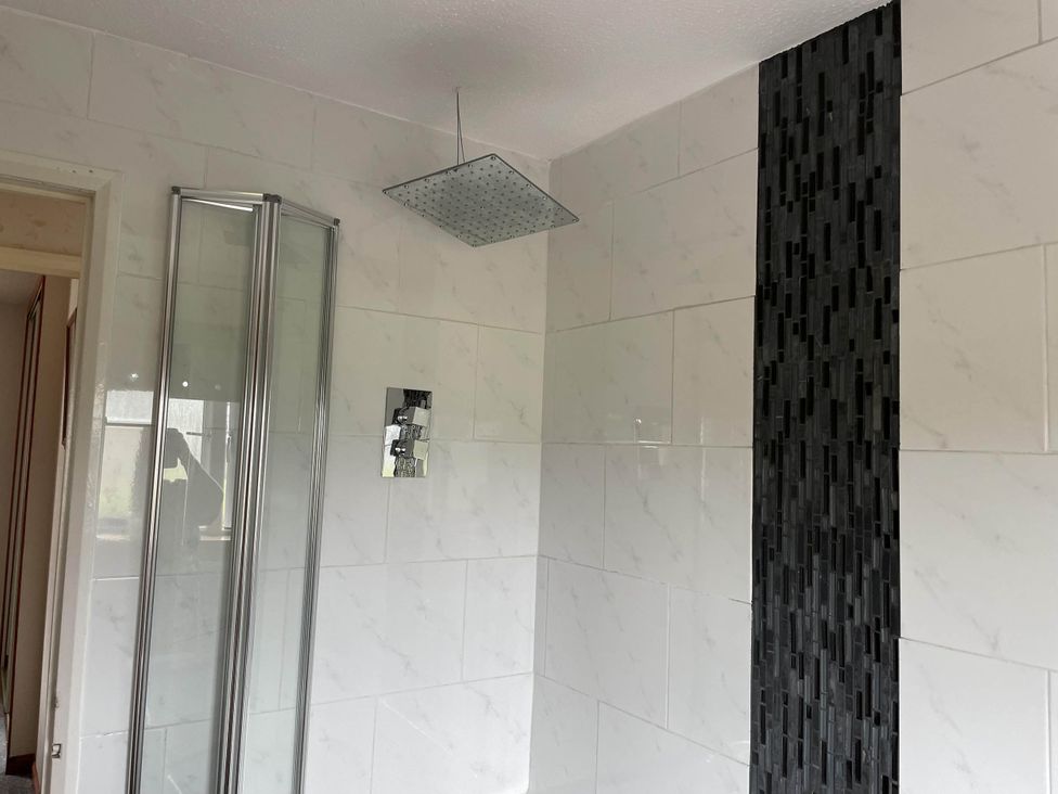 A bathroom with a shower and tiles at Spacious family base with garden near Loch Ness