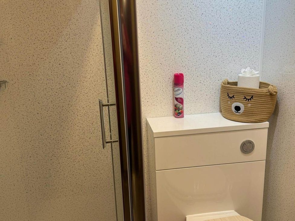 A bathroom with a shower, toilet, spray and a basket at Spacious family base with garden near Loch Ness