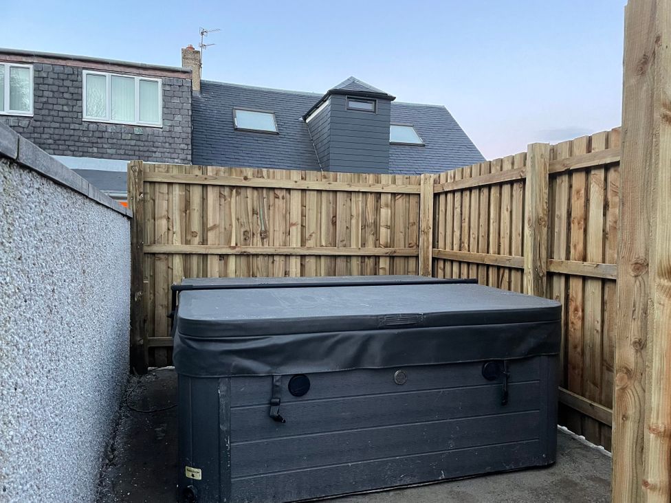 An outdoor area with a hot tub surrounded by a wooden fence at Pet-friendly hot tub retreat near Loch Leven, Kelty