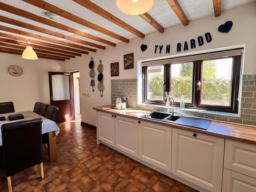 A kitchen with sink and dining table at Dog-friendly farmhouse with Menai Strait views 