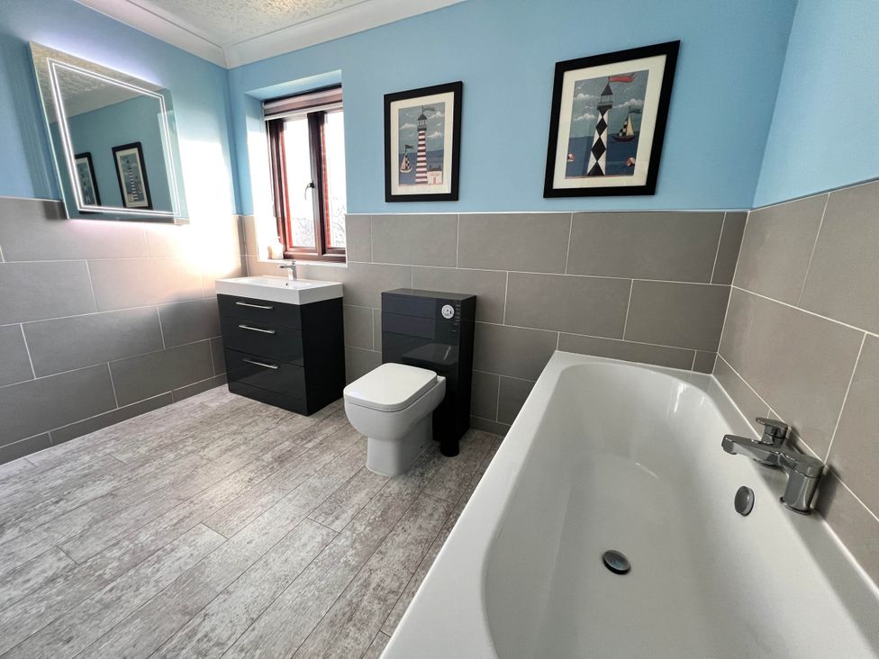 A bathroom with a bathtub, toilet, sink, and mirror in a Dog-friendly farmhouse with Menai Strait views