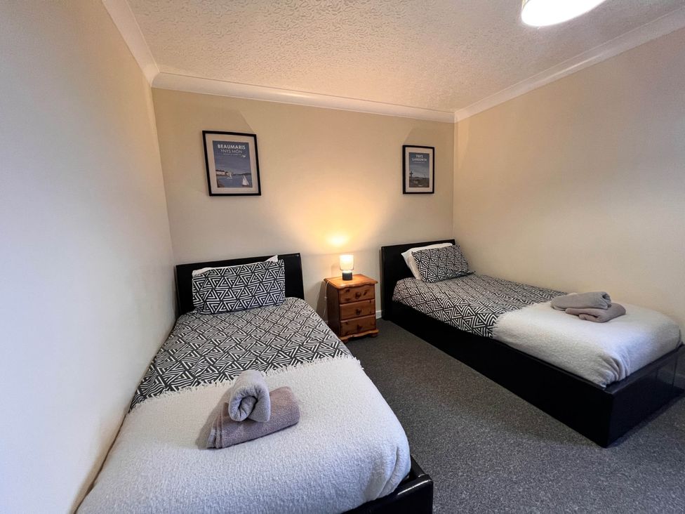 A bedroom with two beds and a bedside table at Dog-friendly farmhouse with Menai Strait views