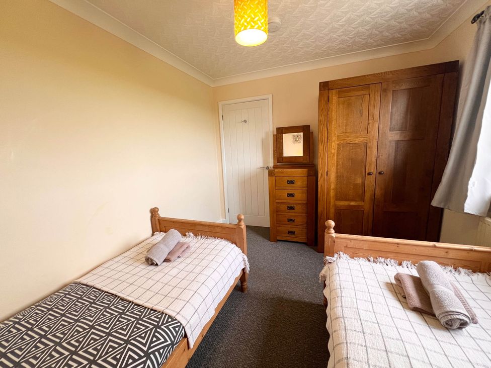 A bedroom with two single beds and wooden furniture in a dog-friendly farmhouse with Menai Strait views