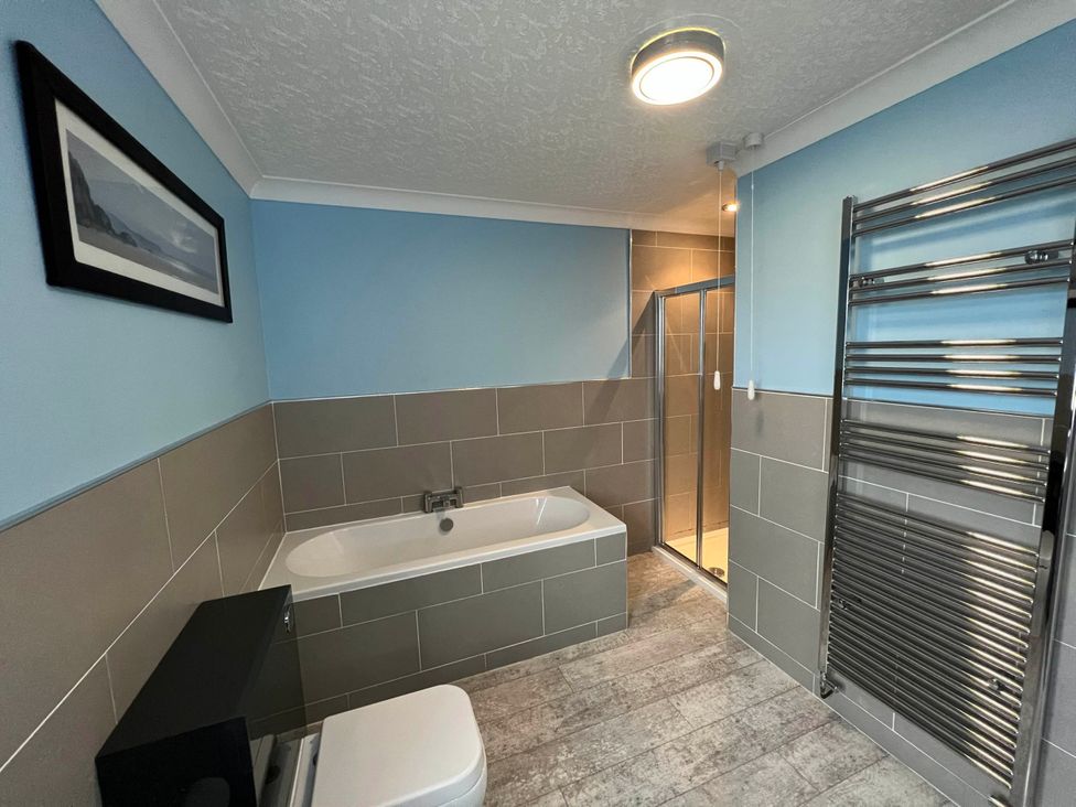 A bathroom with a bathtub and shower at Dog-friendly farmhouse with Menai Strait views