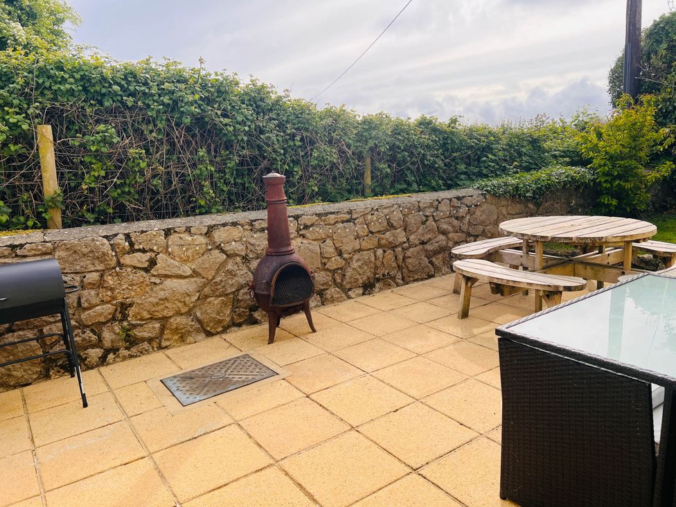 An outdoor patio with a table and benches at Dog-friendly farmhouse with Menai Strait views