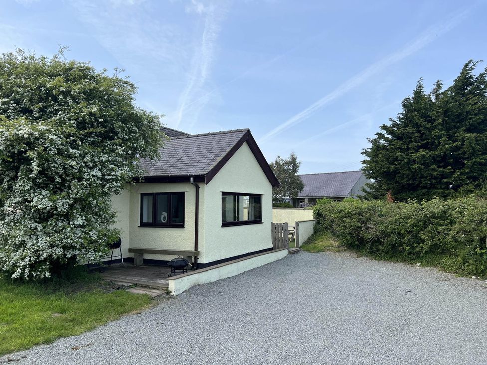 A house with a porch and gravel driveway at Cottage with mountain and sea views, Anglesey