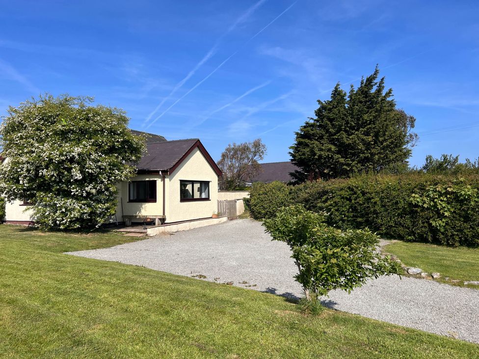 A house with a gravel driveway and trees outside Cottage with mountain and sea views, Anglesey