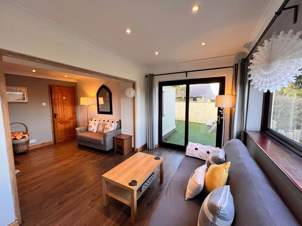 A living room with a sofa, coffee table, and window at Cottage with mountain and sea views, Anglesey