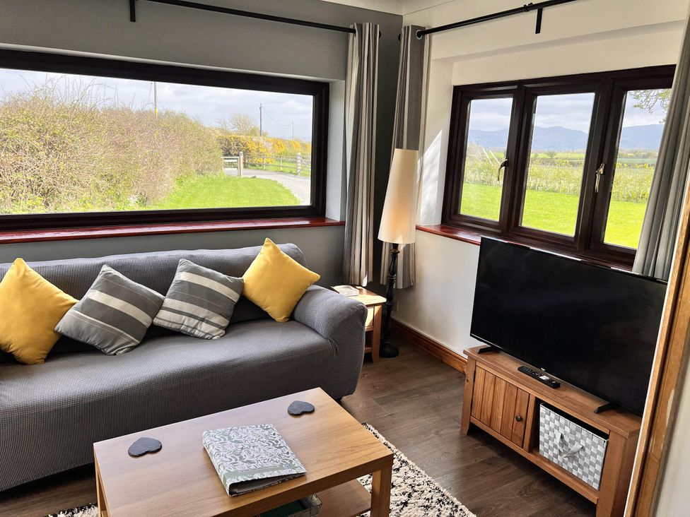 A living room with a sofa and television at Cottage with mountain and sea views, Anglesey