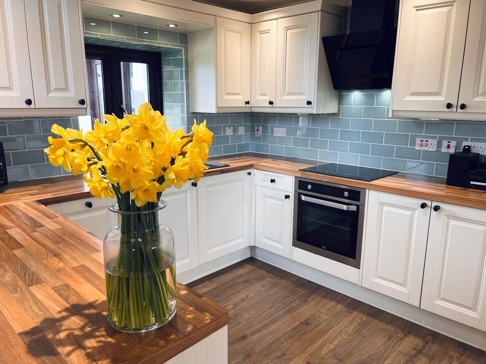 A kitchen with cabinets and a vase of flowers at Cottage with mountain and sea views, Anglesey