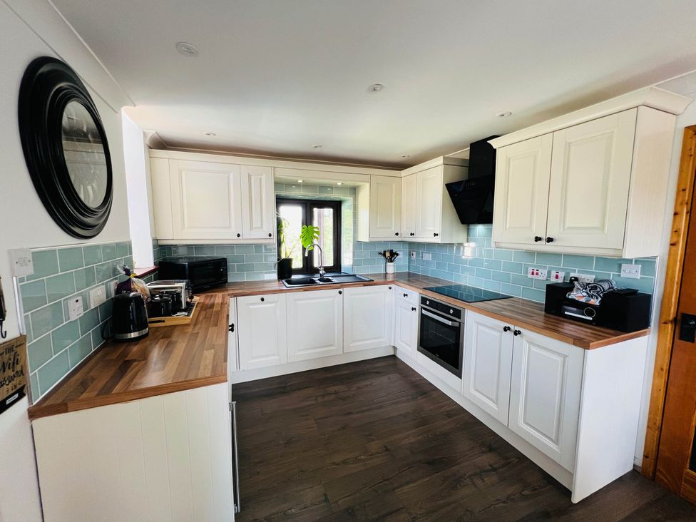 A kitchen with cabinets and appliances at Cottage with mountain and sea views, Anglesey