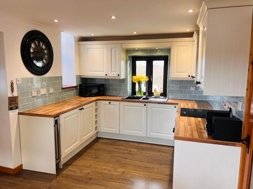 A kitchen with cabinets and a window at Cottage with mountain and sea views, Anglesey